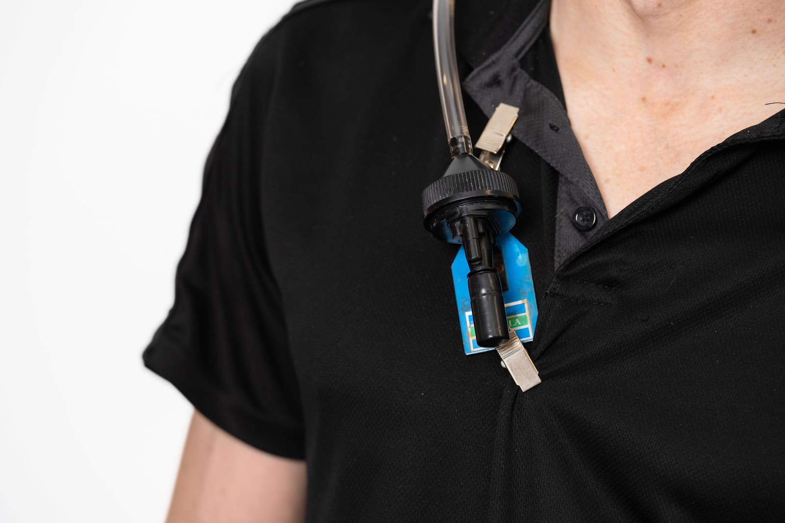 Close-up of an active air sampler attached at a worker's collar for breathing-zone sampling