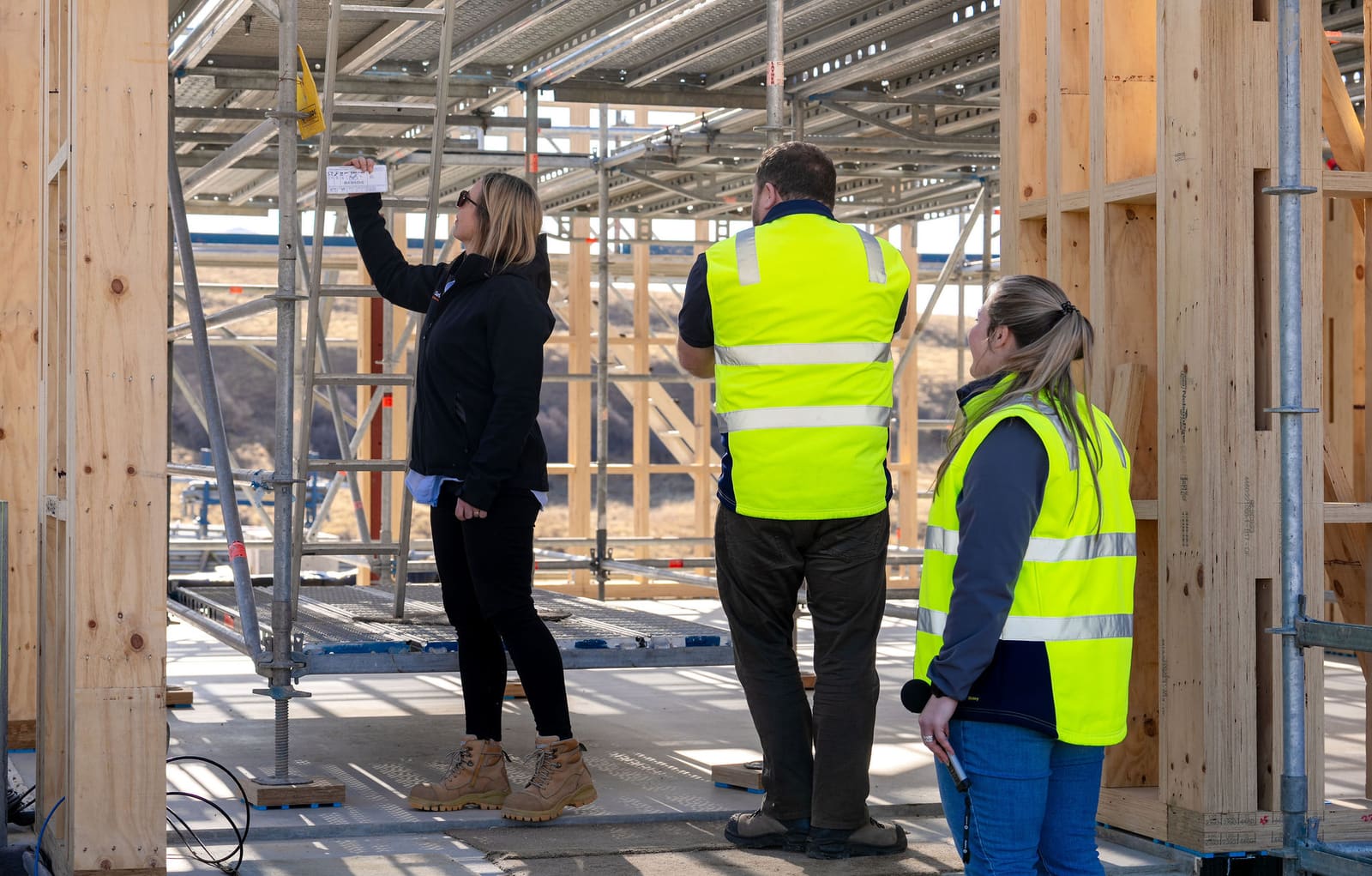 Construction team taking measurements against a timber frame